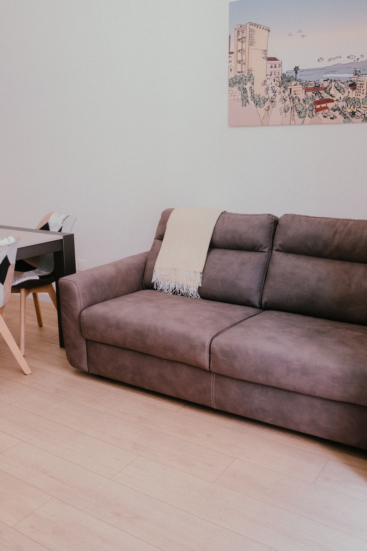 Divano letto con plaid e quadro illustrato di Cagliari